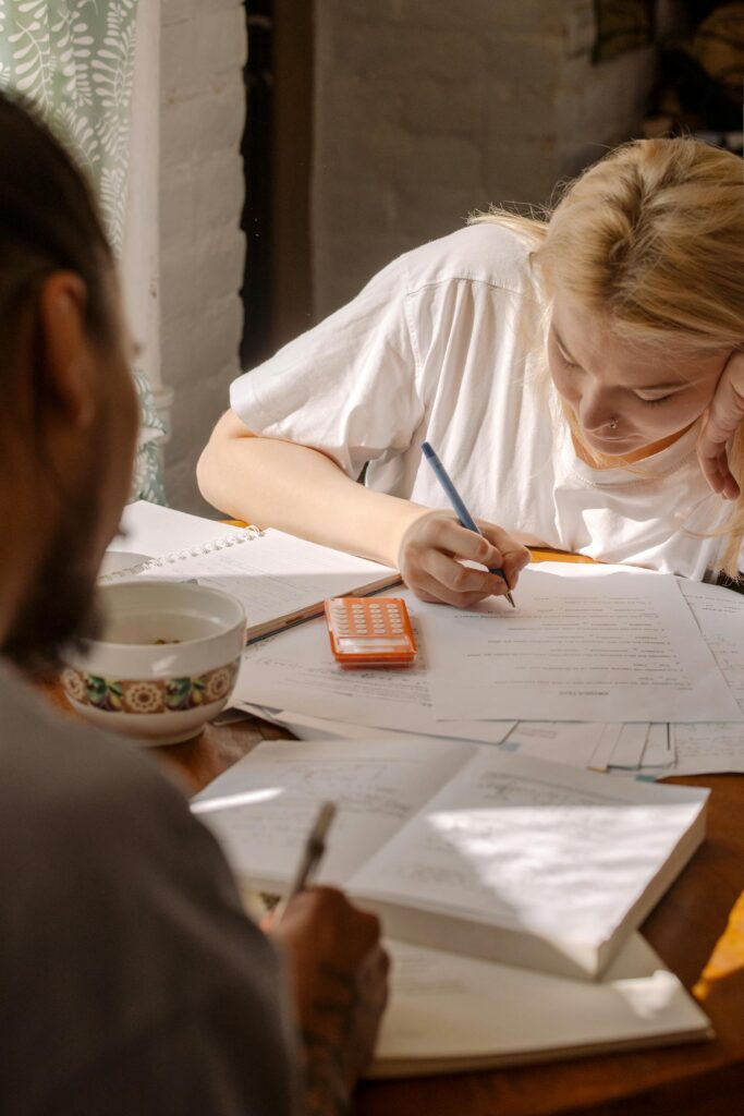Two students concentrating on their homework with textbooks and notes.