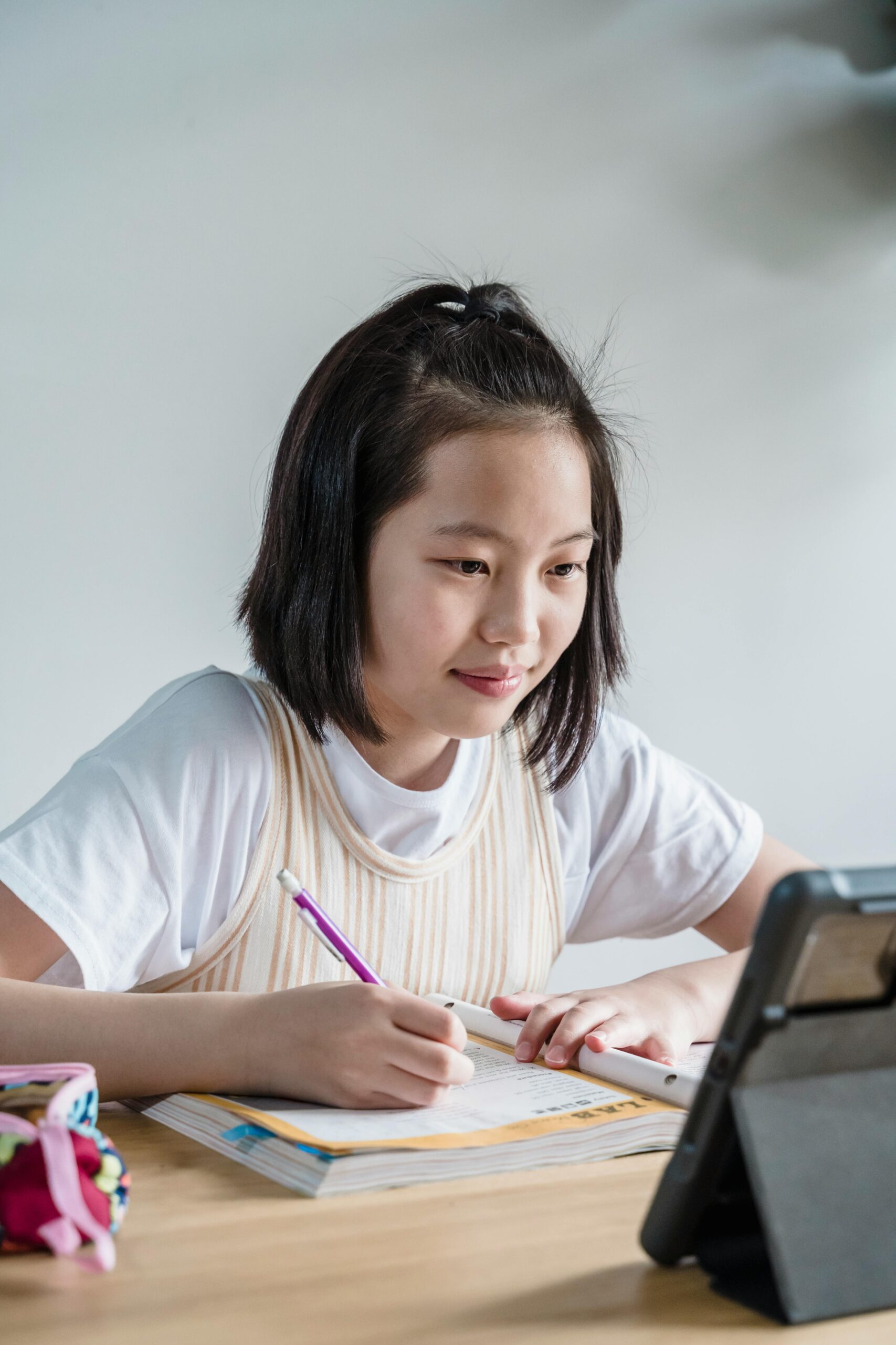 A girl using a tablet for remote learning, focused on her studies at home.